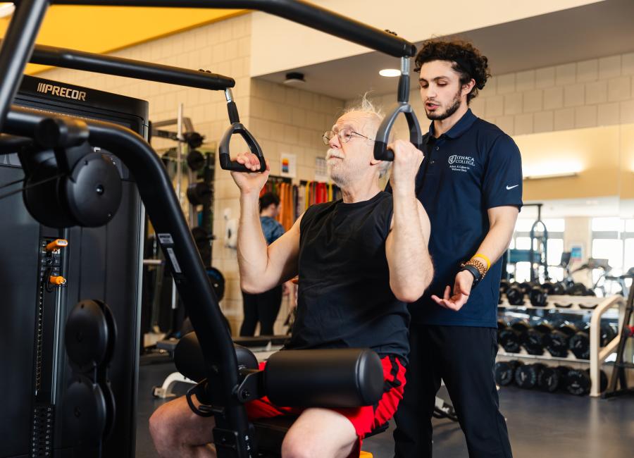 Wellness Clinic student employee assists a member with form.