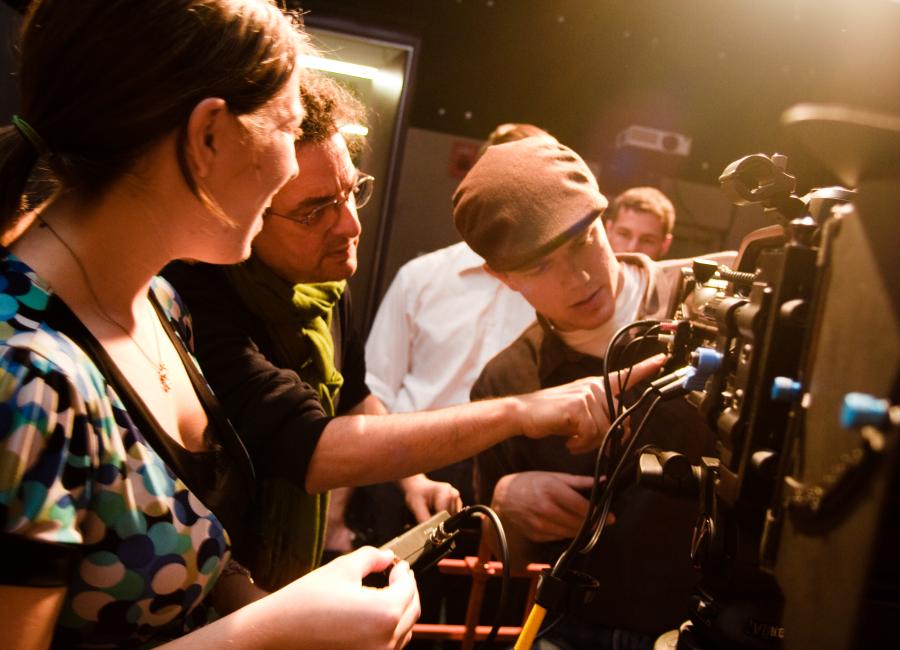 two students and a professor look over recording equipment