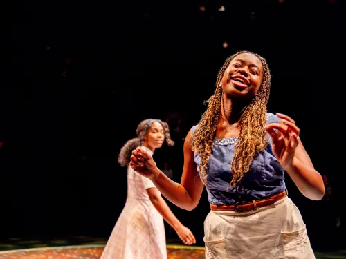Two college students perform in a play on stage.